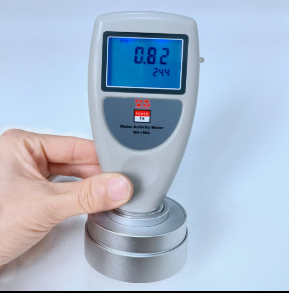 Technician calibrating a digital water activity meter using a certified salt standard in a food safety laboratory.